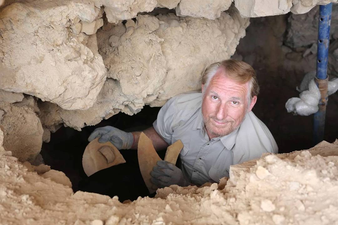 Biblical archaeologist stands in a cave with pieces of an ancient jar that may have contained Dead Sea scrolls